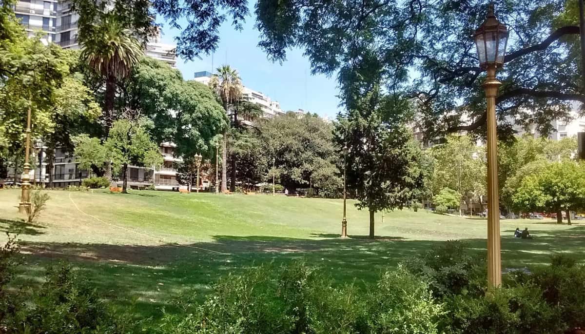 Pelouse et lampadaires du parc des Barrancas de Belgrano, à Buenos Aires, entourés d’arbres et d’immeubles