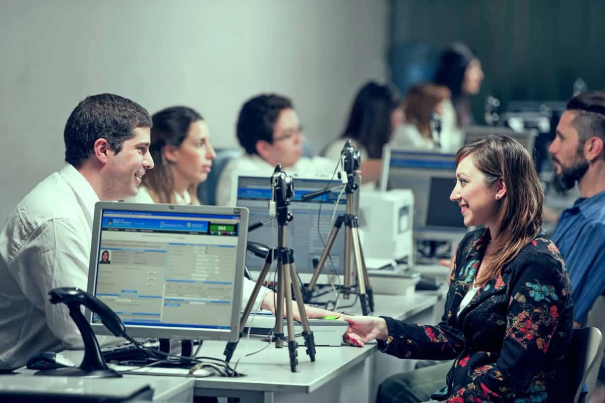 Agents et usagers face aux écrans et aux supports de caméra dans un bureau du RENAPER