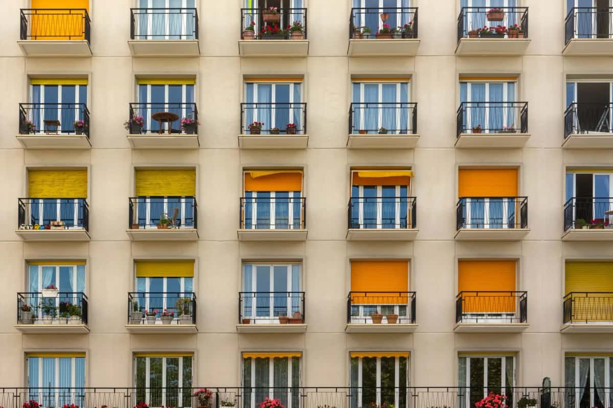 Façade d’un immeuble résidentiel à balcons, avec des stores jaunes et orange