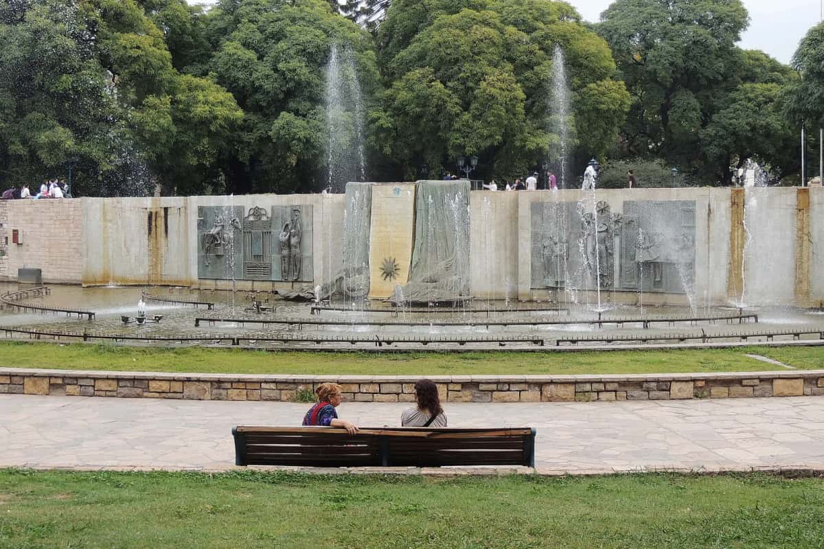 Deux personnes assises sur un banc face à la fontaine de la plaza Independencia, à Mendoza