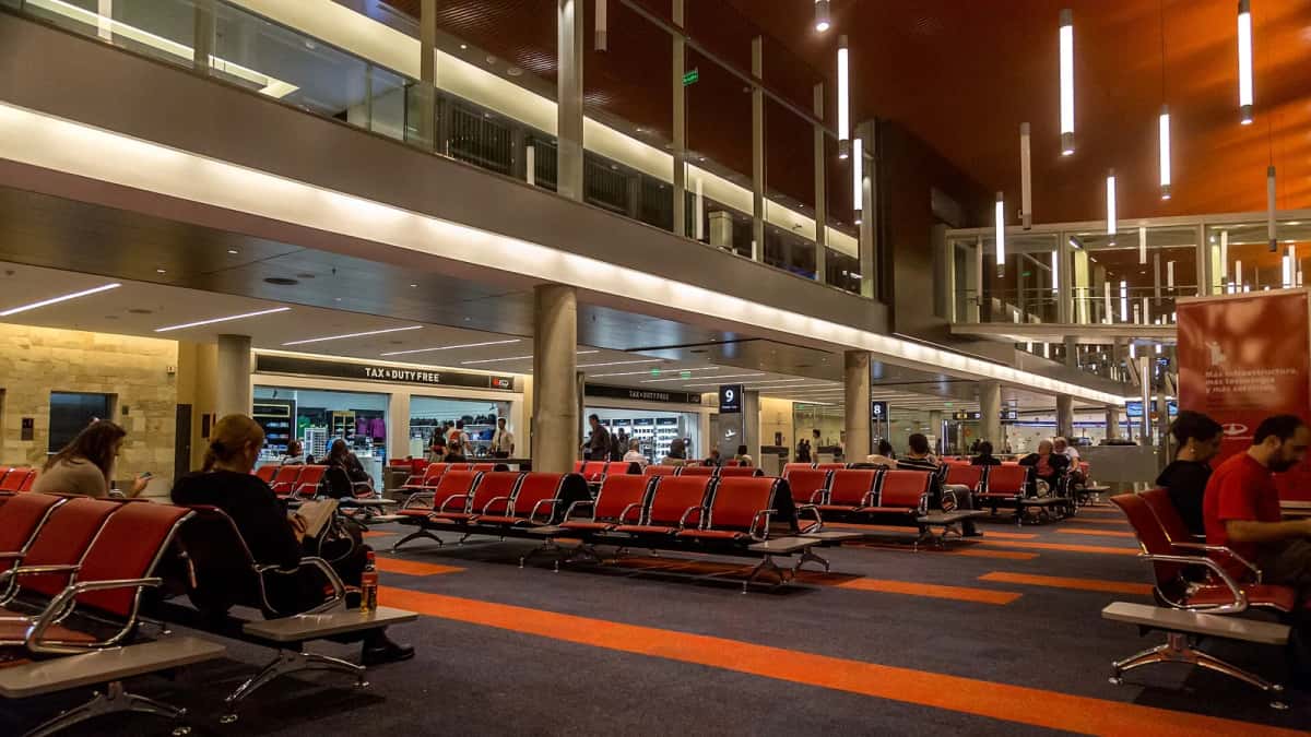 Salle d’attente du terminal B de l’aéroport international Ministro Pistarini, à Ezeiza, près de Buenos Aires, avec des rangées de sièges rouges